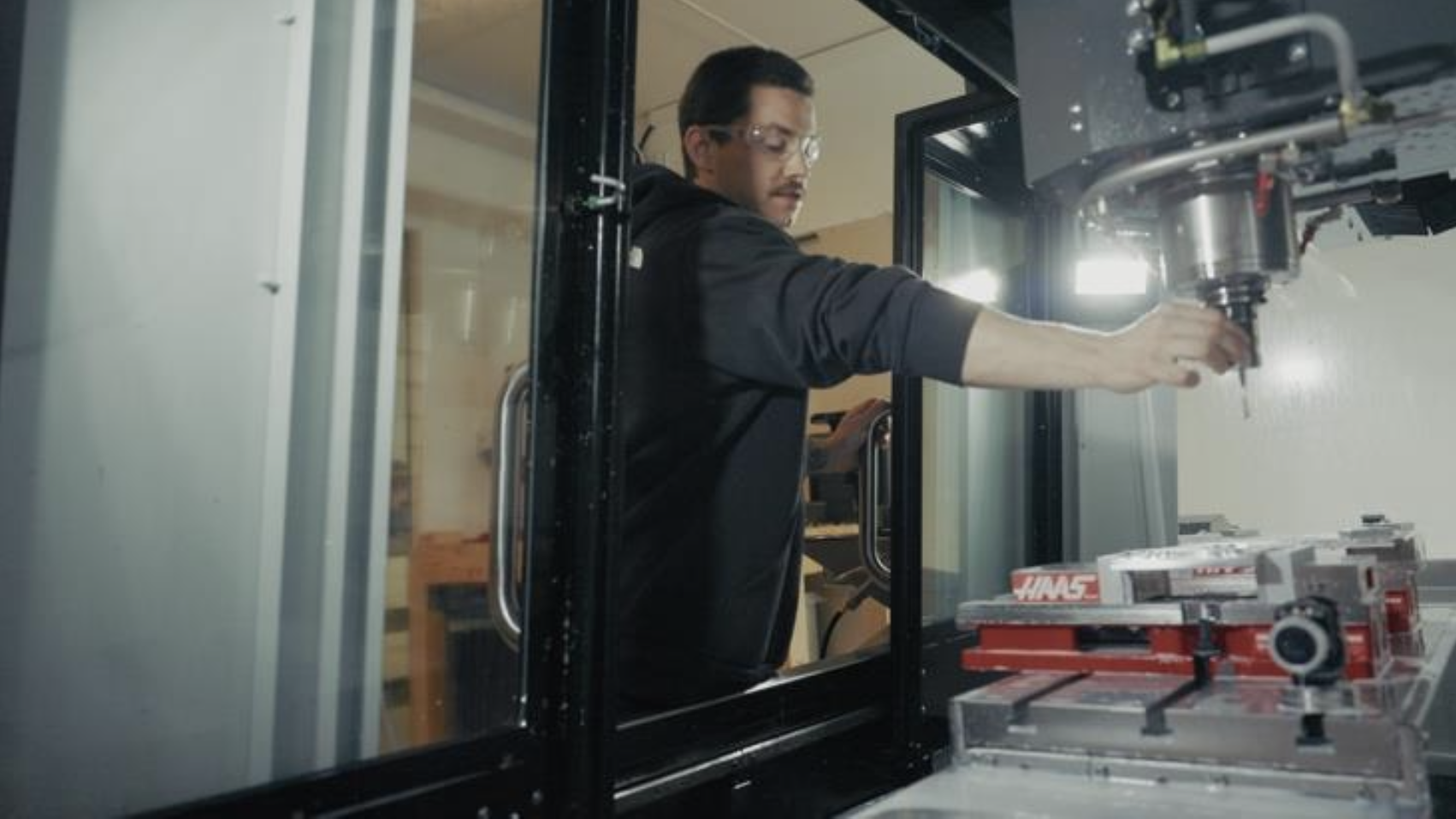 A team member in safety glasses setting up a part in the CNC machine