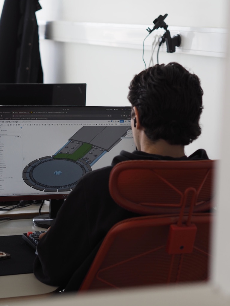A team member at a desk with a 3D model of the blade and arm on screen