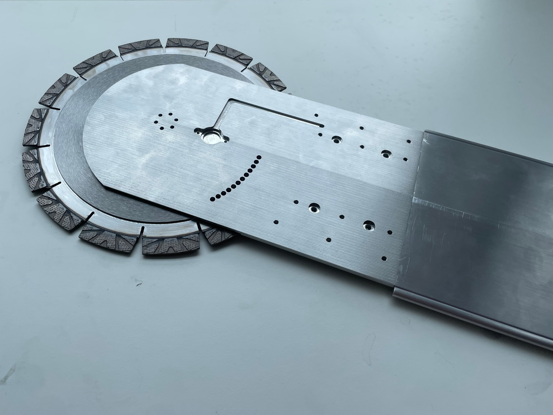 The Rockslice prototype on a workbench: a segmented diamond blade under the machined head plate at the end of the arm