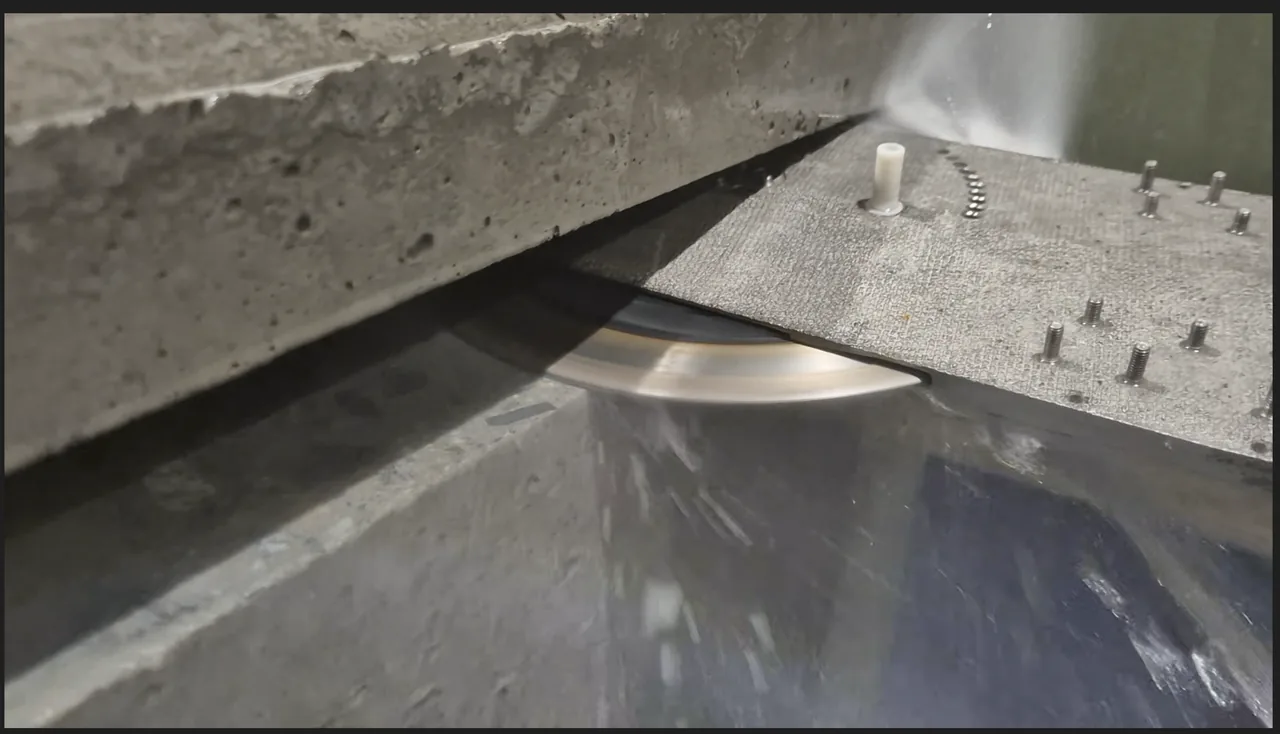 Prototype blade cutting into a concrete test block while water flows across the cut